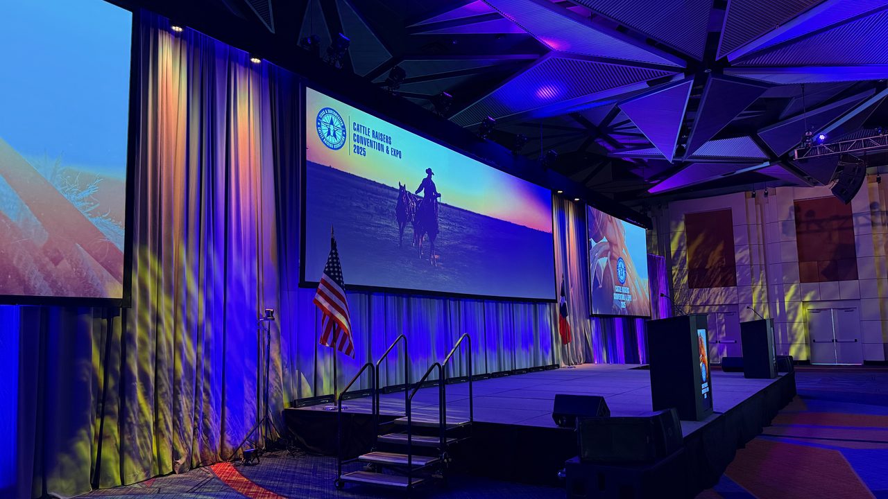 Empty stage with blue wash lighting and western-themed event branding